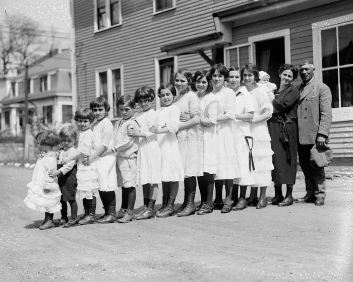 There are as many as thirteen children in this family, all lined up in a row. Now look at the car…